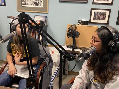 Two students wearing headphones and using recording equipment create a podcast in a recent Chicano Studies class.