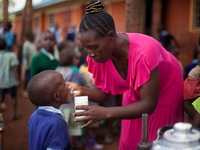 School worker gives a de-worming pill to a young student at a school in Western Kenya