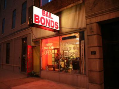 Storefront of a bail bond office on an urban street, with neon lights