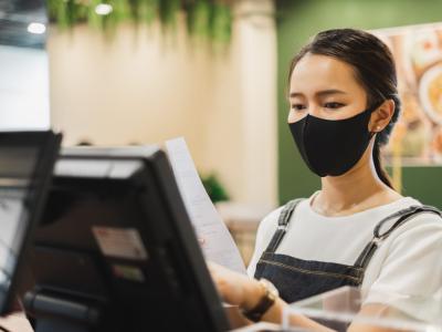 Asian staff restaurant waitress wear protective face mask working in the restaurant with social distancing to protect infection from coronavirus covid-19