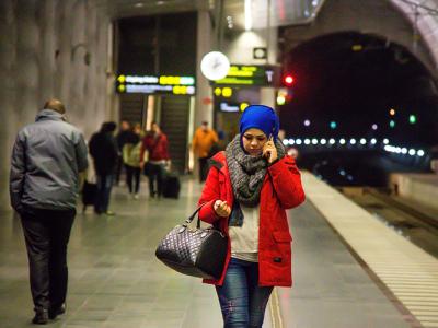 woman walking and talking on a phone at a subway station at night