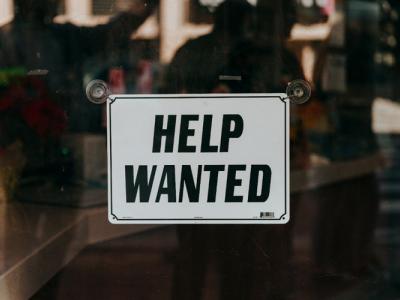 a Help Wanted sign on a glass door