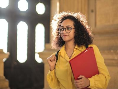 Woman holding red binder inside of a building.