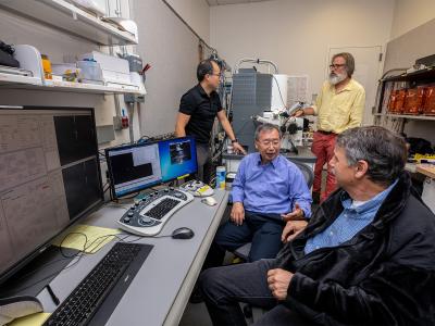 Four scientists converse with each other in a lab.