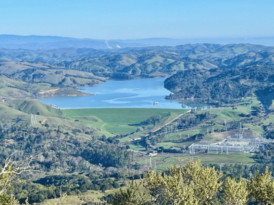 A photo shows a hilly green landscape with a lake in the center