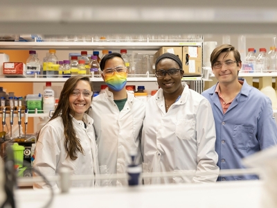 Four researchers posing in a lab wearing lab coats.