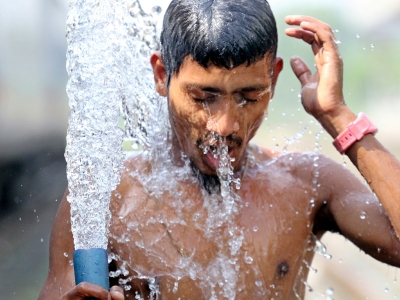 young man spraying water on himself to cool off