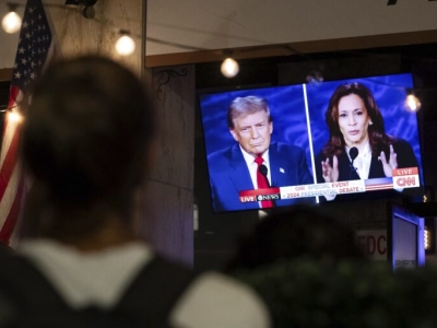 a person stops to watch a screen displaying the US Presidential debate between Vice President and Democratic presidential candidate Kamala Harris and former US president and Republican presidential candidate Donald Trump.