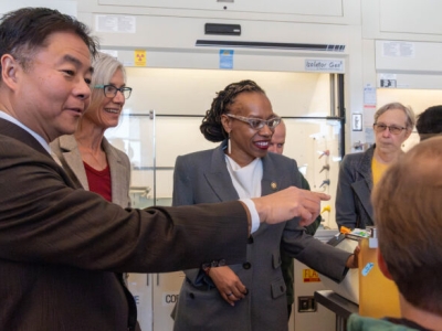 people in a laboratory, one of them pointing toward a computer screen