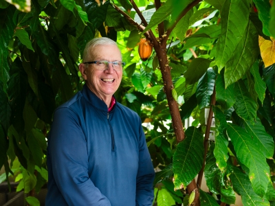 image of man smiling with trees and leaves in the background