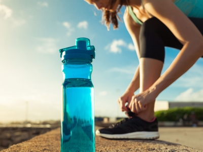 Runner tying her shoe next to a bottle of water.