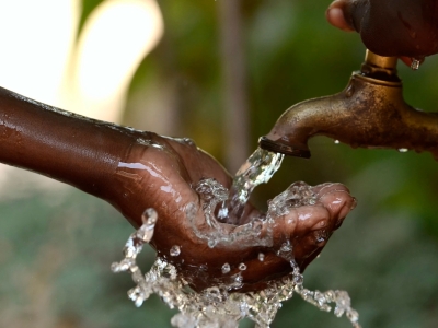 Child's hand receiving water from a spigot.