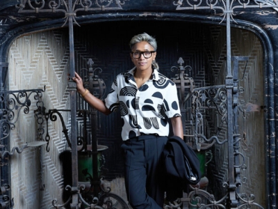 Poulomi Saha stands in front of a huge fireplace surrounded with decorative wrought iron.