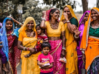 a line of Indian women in colorful saris, with their children
