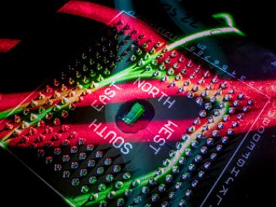 The electronic-photonic processor chip naturally illuminated by red and green bands of light. (Image by Glenn J. Asakawa, University of Colorado)