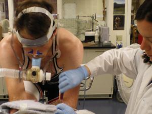 Person getting blood drawn while on stationary bike during study of respiration and lactate metabolism in humans.