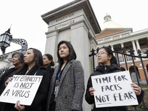 Women from the Asian American Commissions hold protest signs against anti-Asian racism