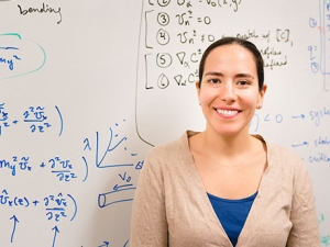 Markita Landry standing in front of a whiteboard wearing a beige sweater