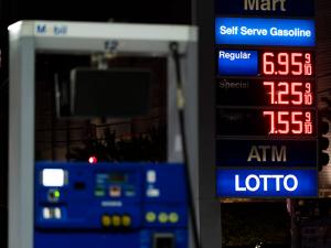 a California gas station at night, with prices in bold red letters starting at $6.95 a gallon.