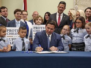 Florida Governor Ron DeSantis signs the controversial "don't say gay" bill, surrounded b school childrenand parents