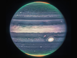 blue and green orb of Jupiter, with a fringe of orange-red auroras at both poles