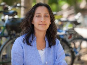 Tina Trujillo, a professor at the Graduate School of Education, looks into the camera. She is sitting in front of a row of bicycles.
