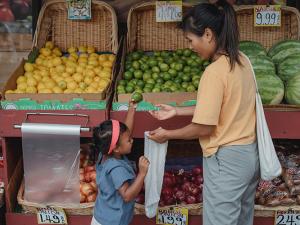 a mom and young child pick out fruit at an outdoor supermarket