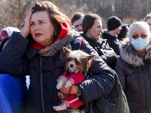 A Ukrainian woman, carrying a small dog in her arms, waits at a border crossing to escape the war in her home country 
