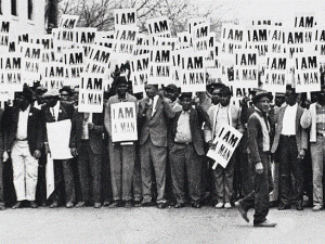 At a 1957 civil rights protest, scores of Black men in a black & white photo carry signs reading &quot;I Am a Man&quot;
