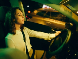 A person is leaning back and closing their eyes while driving a car.