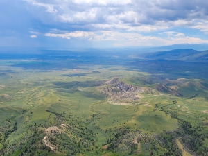 A landscape photo of a green valley and mountains with a blue sky
