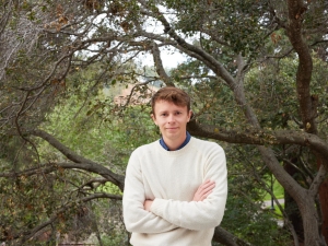headshot of man standing in front of trees
