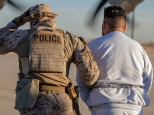 A photo showing from behind a person in military fatigues and a sidearm in a holster, with a 