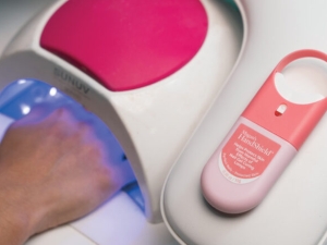 a hand inserted under a hood illuminated by blue light