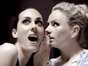 woman whispering into the ear of another woman