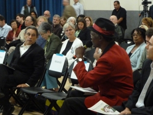 people in an audience, one with a microphone