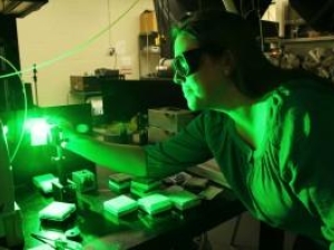 person in lab with green light glowing on person and equipment