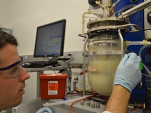Man with eye protection working with equipment holding a liquid