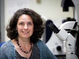 woman sitting next to a microscope