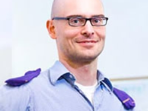Pieter Abbeel smiling with purple socks on his shoulders