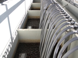 multiple hoses extending into a vat of dark liquid